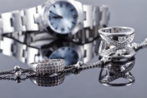 Silver rings of different styles and silver chain on the background of reflections women's watches